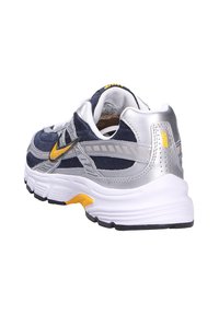 Scarpa da ginnastica navy e argento dal design elegante, con una tomaia texturizzata, accenti gialli e una suola bianca imbottita.