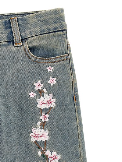 Jeans di denim con una sfumatura azzurro chiaro, caratterizzati da ricami floreali rosa e bianchi lungo il lato per un tocco decorativo.