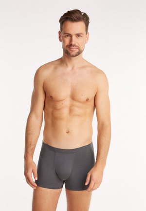 Boxer-briefs gris en tissu lisse et extensible avec un ajustement serré, dotés d'une taille mi-haute et d'un design de poche frontale soutenante.