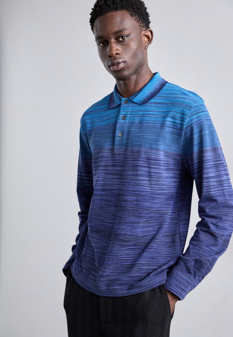 Langærmet polo skjorte i gradient blå nuancer med vandrette striber, tre-knaps placket og ribbet krave. Blød stof tekstur.