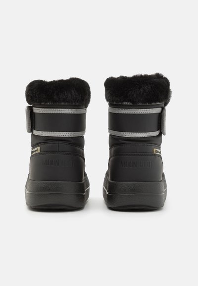 Bottes d'hiver noires avec garniture en fausse fourrure, matériau lisse, sangles réglables et semelles texturées. Marque visible à l'arrière.