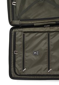 Interno di una borsa da viaggio verde oliva con tasca in rete, tre compartimenti con zip e etichetta con logo, caratterizzata da un tessuto liscio e cerniere resistenti.