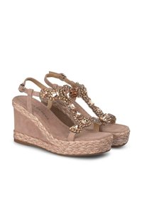Las sandalias de cuña beige presentan una correa de tela texturizada adornada con piedras preciosas, una suela de yute trenzado y una correa ajustable en el tobillo.