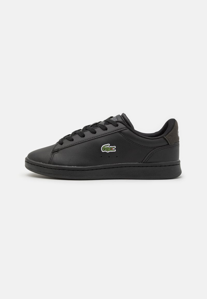 Scarpa sportiva nera con tomaia sintetica liscia, chiusura con lacci e logo ricamato verde. Presenta una suola in gomma nera strutturata.