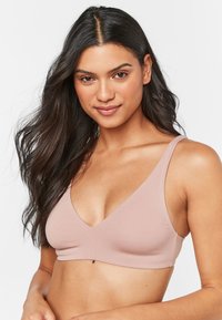 Helle rosa Bralette mit tiefem V-Ausschnitt, breiten Trägern und einer glatten, weichen Textur. Nahtloses Design ohne zusätzliche Verzierungen.