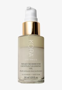  bouteille en verre avec un fond arrondi, liquide transparent beige clair, capuchon de pompe métallique doré, et texte noir indiquant "KORA ORGANICS MILKY MUSHROOM".