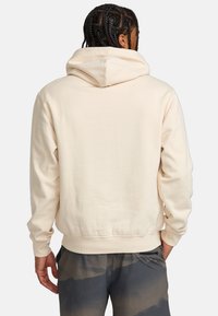 Helle beige Kapuzenjacke aus weichem, strukturiertem Stoff, mit einer großen Kapuze und gerippten Bündchen. Das Design hat eine lockere Passform und zeigt keine sichtbaren Logos.