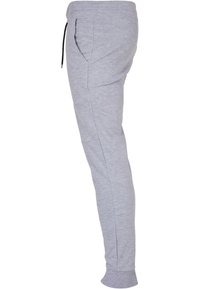 Pantalons de jogging gris en tissu doux, avec une taille élastique et cordon de serrage, poches latérales et jambes fuselées avec bords côtelés.