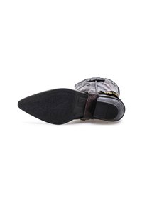 Crna kožna čizmica do gležnjeva s teksturiranim detaljima, šiljatim vrhom i niskom petom. Sadrži bočnu traku s dekorativnom kopčom.