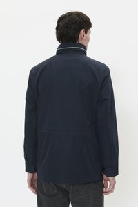 Chaqueta impermeable de color azul marino con un cuello alto, mangas largas y una textura suave. Presenta una costura visible en la parte posterior y puños ajustados.