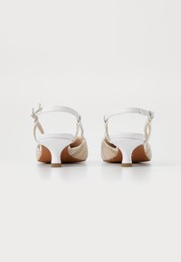 Sandalias de tacón blancas con material trenzado multicolor en los lados y una correa en el tobillo. Tacones pequeños y anchos que ofrecen estabilidad.