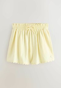 Világossárga elasztikus derékpántos rövidnadrág masnival az elején és hullámos szegéllyel, az oldalon egy kis kerek fém logóval.
