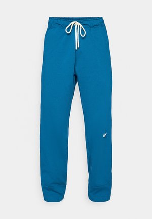 Blå joggebukser med justerbar midje, ribbede ermer, myk tekstur og en liten logo på venstre side. Allsidig og komfortabel design.