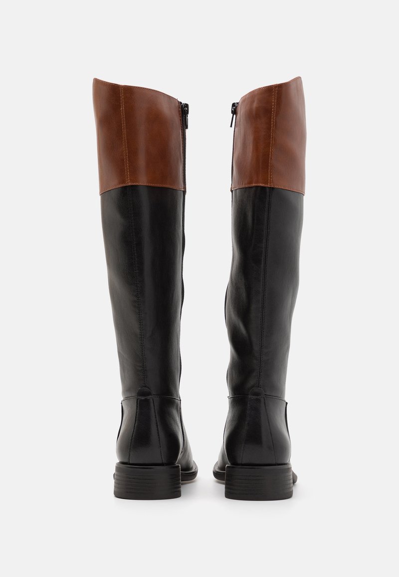 Bottes noires en cuir montantes jusqu'au genou avec un revers en cuir marron, dotées d'une fermeture éclair sur le côté et d'un petit talon empilé. Texture lisse et design épuré.