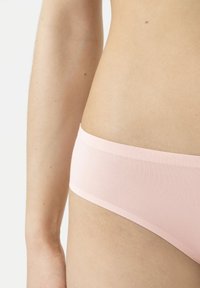 Lichtroze string met een zachte, gladde textuur en een laag model, met een minimalistisch ontwerp en een elastische tailleband.