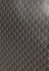 Surface noir texturé avec un motif répété de lignes diagonales dorées et de cercles formant des formes de diamant.