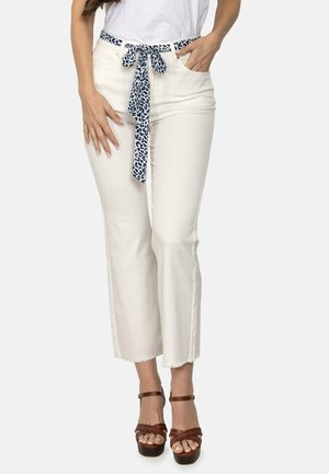 Pantalones blancos cortos con un cinturón de lazo de estampado de leopardo azul, con un dobladillo deshilachado y un ajuste slim. Combinados con sandalias de plataforma marrones.