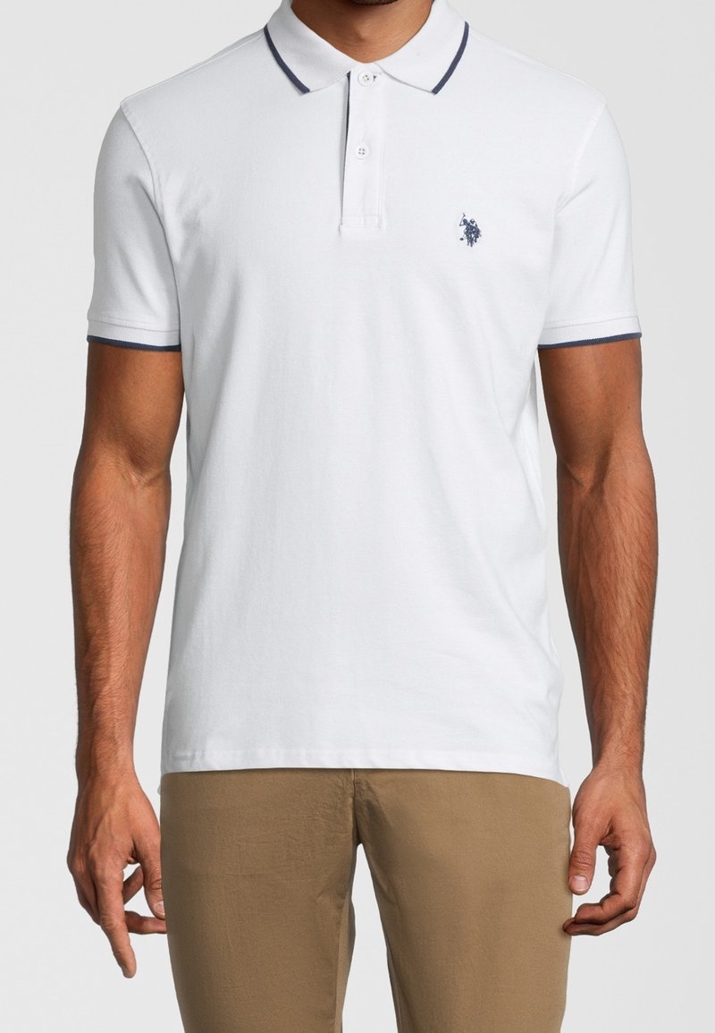Polo blanc à manches courtes avec un col marine et des accents assortis sur les manches ; comporte un petit logo brodé sur la poitrine.