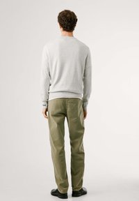 Suéter gris con dobladillo y puños acanalados, combinado con pantalones verde oliva. Zapatos negros completan el atuendo. Diseño limpio y minimalista.
