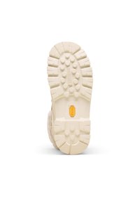 Semelle extérieure de couleur crème avec une empreinte en caoutchouc texturée, présentant un logo Vibram proéminent ainsi que des motifs circulaires et en zigzag pour une meilleure adhérence.