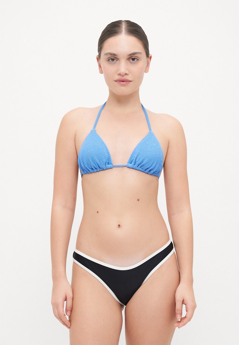 Kék kötött háromszög bikini felső vékony pántokkal, fekete bikini alsóval párosítva, amely fehér kiegészítőkkel rendelkezik, sima textúrájú és testhezálló kialakítású.