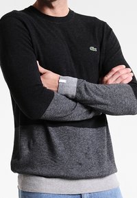 Svart och grå blockfärgad crew-neck tröja gjord av mjuk tyg med ribbade manschetter och nederkant, med en liten logotyp på bröstet.