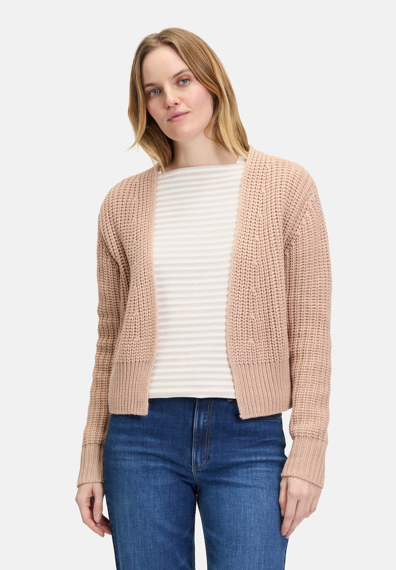 Roze gebreide cardigan met open voorkant, geribbelde boorden, een textuurpatroon en zachte garen. Gedragen over een gestreepte lange mouwen shirt en blauwe jeans.