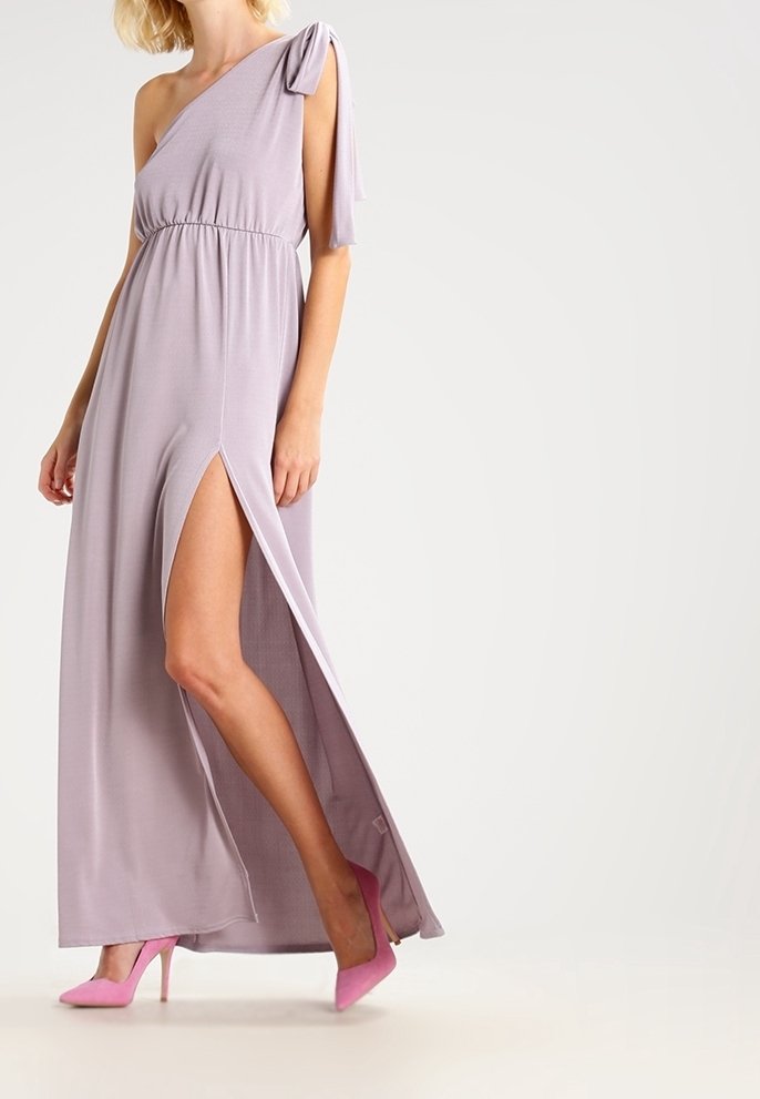 Maxiklänning i ljus lavendelfärgad tyg, med en axel-design, elastisk midja och en slits på sidan, kombinerad med rosa högklackade skor.