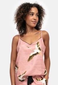 Roze camisole met zwarte bies, voorzien van een kraanvogelprint in wit en gouden accenten. Lichtgewicht stof met verstelbare bandjes.