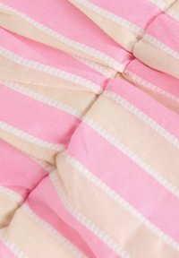 Vêtement sans bretelles en rayures rose et beige, avec une texture douce et une délicate bordure blanche le long des bords, comprenant des détails de tissu froncé.