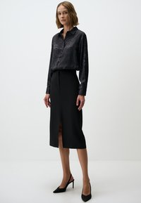 Black floral blouse with a collar, button-up front, and long sleeves, paired with a knee-length black skirt featuring a front slit.