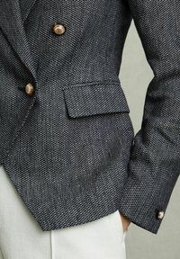 Námořnický dvouřadý blazer s texturovaným vzorem, zdobený zlatými knoflíky a módním klopovým límcem. Viditelné boční kapsy.