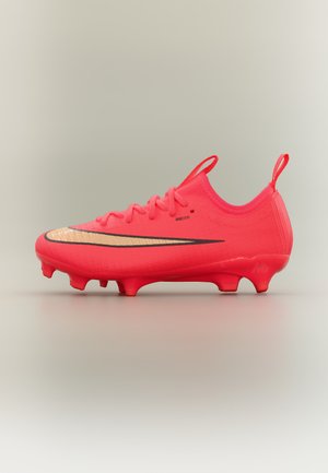 Scarpa da calcio rosso brillante con swoosh Nike oro e nero, lacci e tacchetti sagomati sulla suola, mostrata di lato su sfondo semplice.