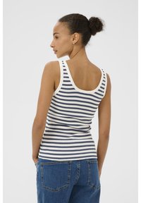 Top a righe in blu navy e crema, realizzato in tessuto a coste. Caratterizzato da spalline larghe e scollatura rotonda. Abbinato a jeans in denim blu.