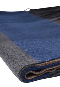 Coperta in lana caratterizzata da sezioni grigio scuro, blu e marrone con una finitura morbida e testurizzata, arrotolata con una maniglia in tessuto a soffietto per appenderla.