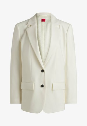 Valkoinen bleiseri, jossa on terävä kaulus, kaksi etutaskua ja kaksi mustaa nappia. Sisäpuolella on hillitty logo-kuvio. Sujuva rakenne.