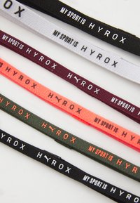 Kleurrijke stoffen banden in zwart, wit, bordeaux, oranje en groen met bedrukte tekst: "MIJN SPORT IS HYROX" en logo-accenten van Puma.