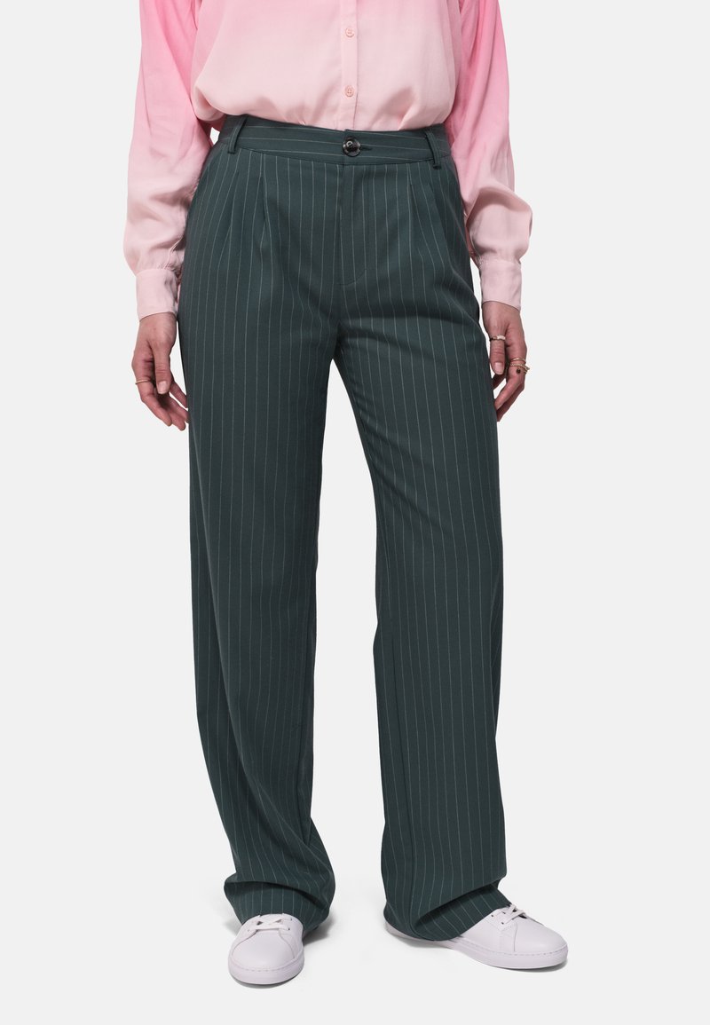 Donkergroene gestreepte broek met een relaxte pasvorm, met een vlakke voorkant, zijzakken en gecombineerd met witte sneakers.
