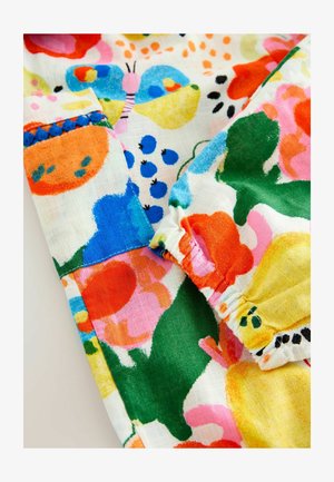 Livlig blommönstrad lättvikts tyg i orange, rosa, gröna och blå nyanser med volangdetaljer och stickade accenter.