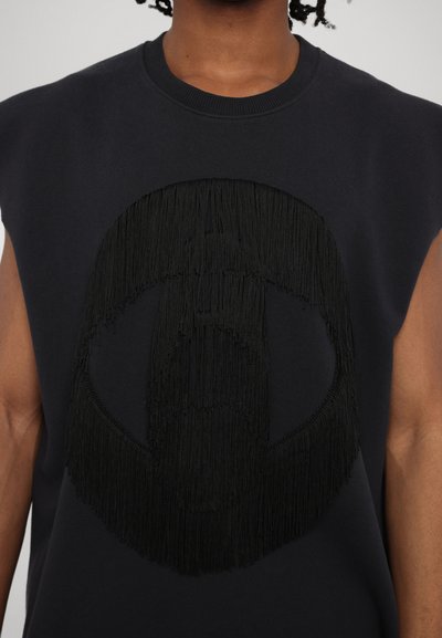 Melna bez piedurknēm sporta jaka ar lielu, teksturētu frizi grafiku centrā. Izgatavota no mīksta auduma ar apaļu izgriezumu.