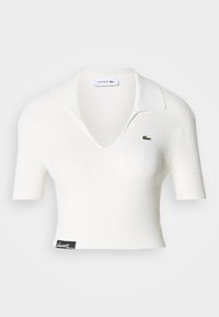 Weißes geripptes, kurzes Polohemd mit V-Ausschnitt, kurzen Ärmeln und grünem Lacoste-Krokodil-Logo auf der linken Brust. Schwarzes Etikett am Saum.