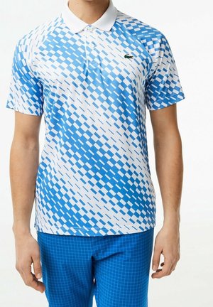 Homme portant un polo à manches courtes avec un motif à carreaux bleu et blanc et un pantalon à carreaux bleu.
