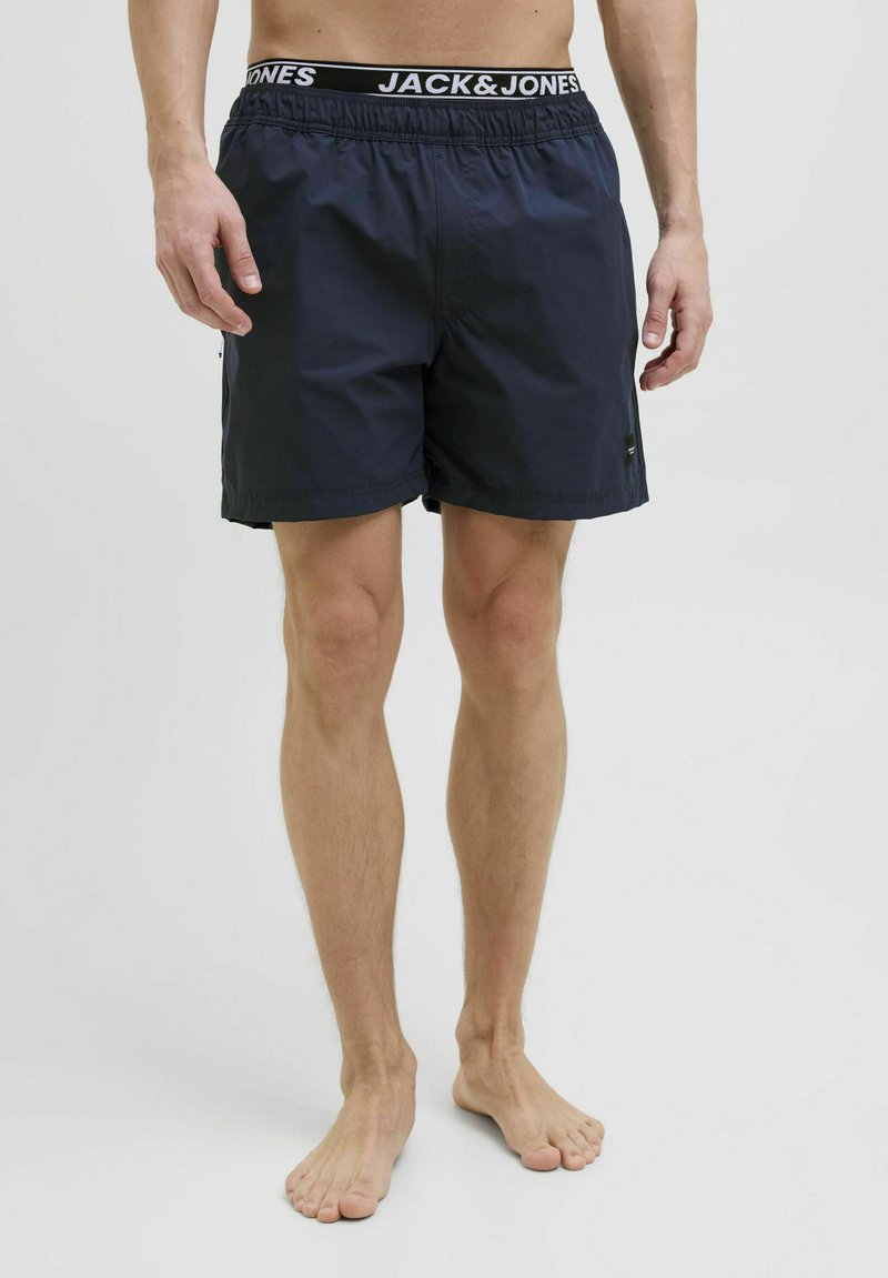 Tengerészeti úszónadrág elasztikus derékkal, amelyen a "JACK & JONES" felirat található. Simító, könnyű anyag, oldalsó zsebek és klasszikus szabás.