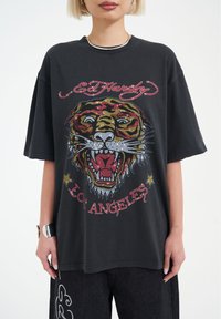 Svart grafisk t-shirt med en färgglad tigerdesign prydd med rhinestones, "Ed Hardy"-logotyp och texten "Los Angeles" i röd.