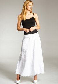 Weißes Leinen-Maxi-Rock mit einem breiten, weichen Bund. Getragen mit einem schwarzen eng anliegenden Tanktop und kombiniert mit weißen High-Heels.