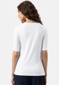 Wit T-shirt met korte mouwen, ronde hals en een gladde textuur, met een aangesloten pasvorm en een subtiele afwerking aan de zoom.