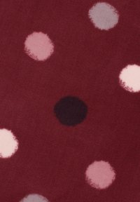 Cotton fabric in deep red with scattered round dots in varying shades of pink and one black dot. Soft texture with blurred edges on dots.