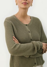 Olivgrüner gestrickter Cardigan mit Knopfverschluss, langen Ärmeln, gerippten Bündchen und strukturiertem Strickmuster. Weiches Material mit lockerer Passform.