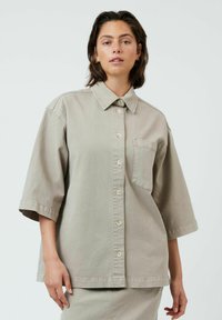 Chemise surdimensionnée gris clair à boutons en coton, avec un col, des manches courtes et une poche poitrine.