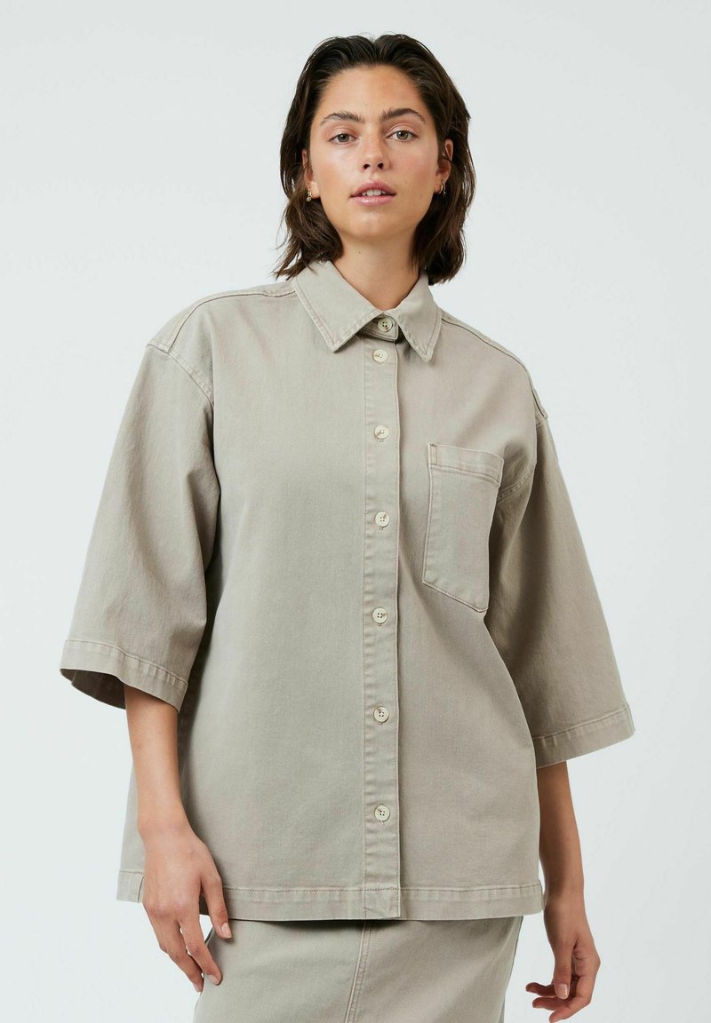 Chemise surdimensionnée gris clair à boutons en coton, avec un col, des manches courtes et une poche poitrine.